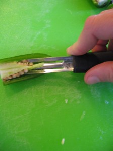Using a vegetable peeler to remove the ribs and seeds from a jalapeno pepper